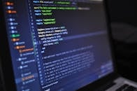 Close-up of a computer screen displaying programming code in a dark environment.