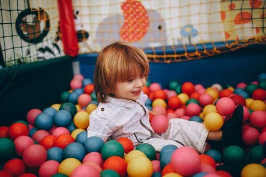 A cheerful child enjoying playtime in a colorful indoor ball pit.